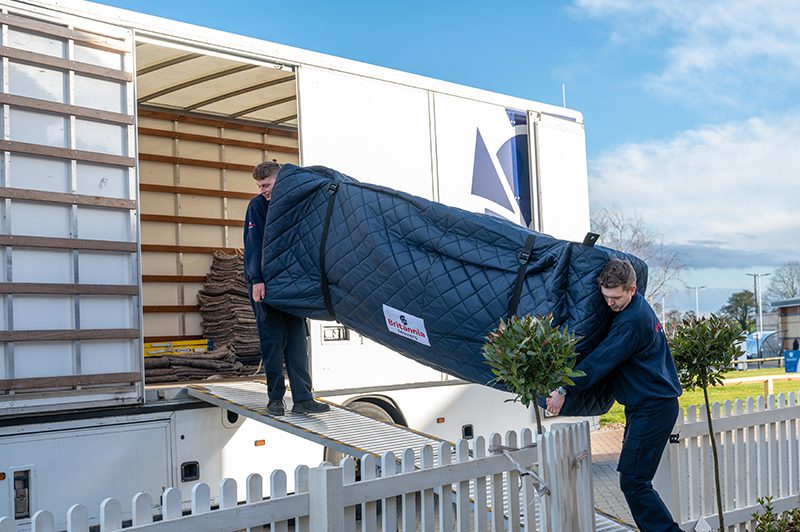 Britannia Alan Cook Removals & Storage team unloading a large sofa wrapped in a protective padded cover from a removals lorry