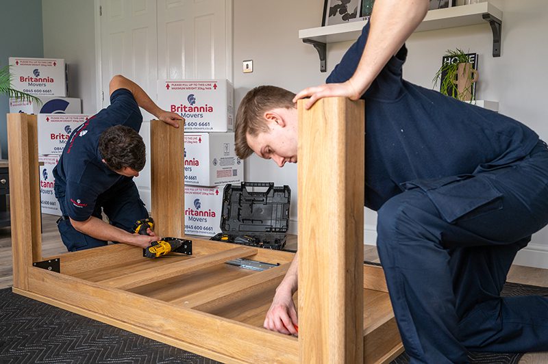 Britannia Alan Cook Removals & Storage team members demantling a dining table prior to wrapping in a protective cover and loading onto the removals lorry