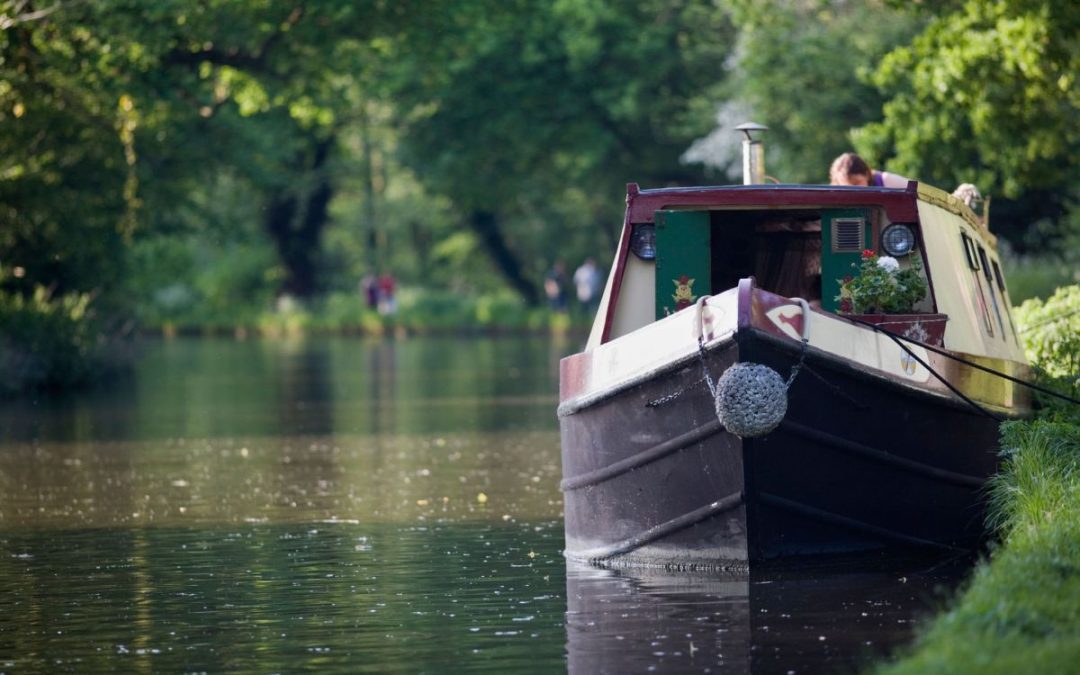 A canal boat moored at the side of a picturesque river location
