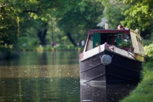 A canal boat moored at the side of a picturesque river location