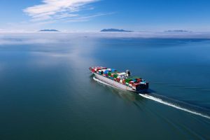 Large container ship fully laden with shipping containers sailing on a calm ocean