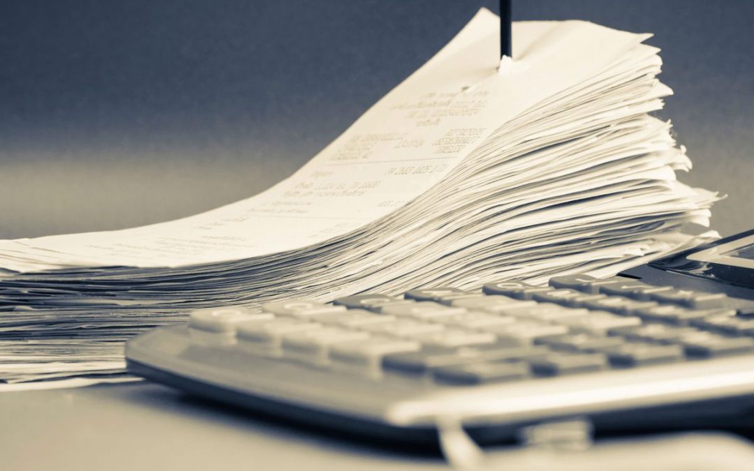 Piles of purchase receipts next to a large accounting calculator