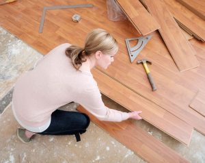 A lady putting together sections of laminated wooden flooring