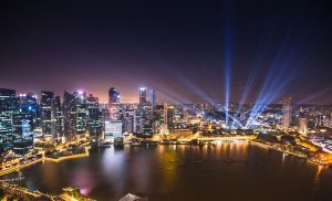 A spectacular nighttime cityscape scene with high rise buildings and harbour area with an amazing light show
