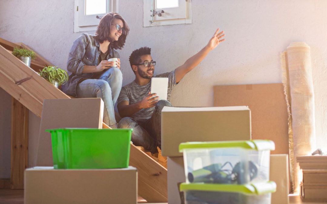 A happy couple sat on the stairs discussing exciting plans for their new home, surrounded by removals boxes