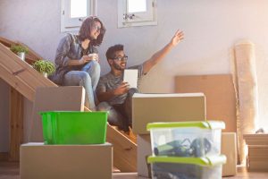 A happy couple sat on the stairs discussing exciting plans for their new home, surrounded by removals boxes