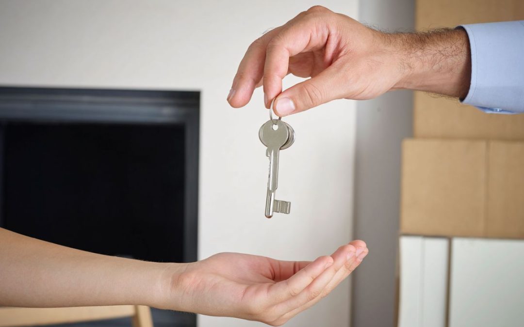 A mans hand holding keys to a new home about to drop them into the open palm of a ladies hand
