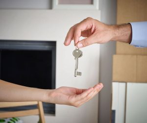 A mans hand holding keys to a new home about to drop them into the open palm of a ladies hand