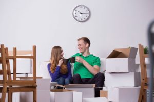 A couple sat with cups of coffee celebrating a house move