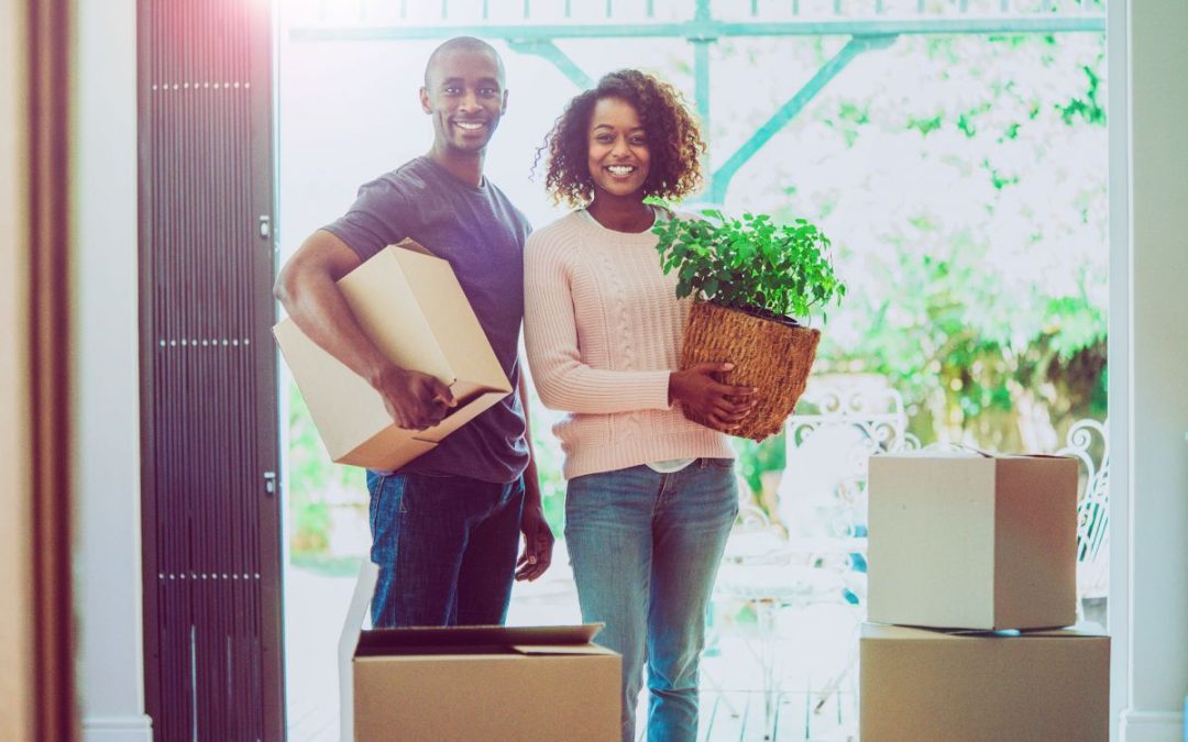 A happy couple with removals boxes and a house plant in their new home