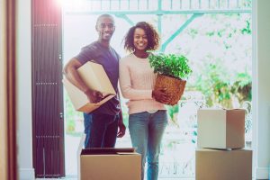 A happy couple with removals boxes and a house plant in their new home