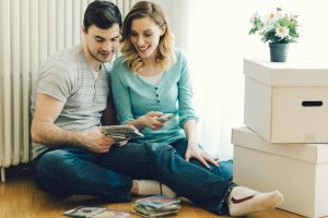 A young couple sat on the floor looking at a selection of CDs before packing them in cardboard boxes