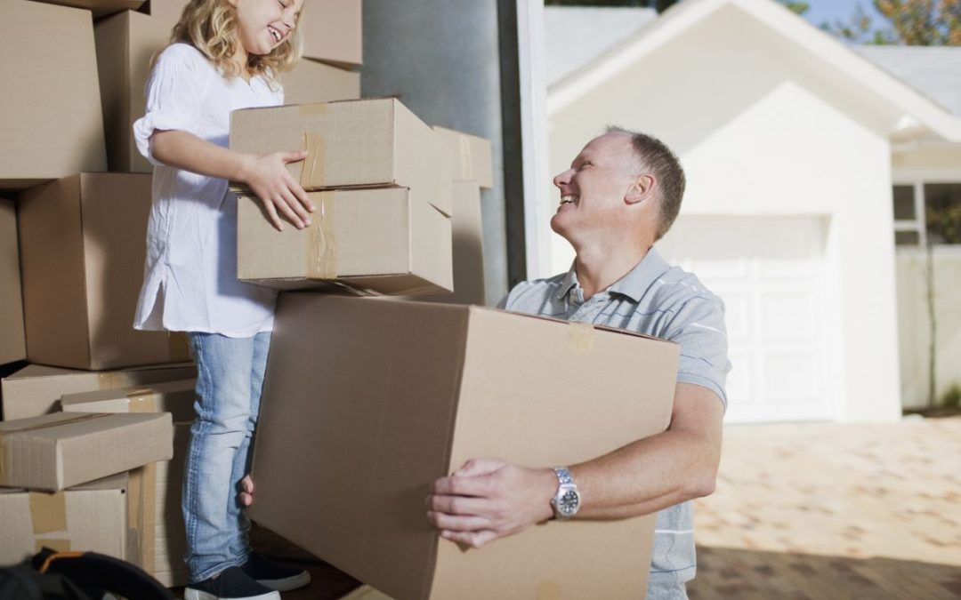 A happy scene of a father and young daughter unloading boxes in front of their new home