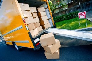 A removals van filled with cardboard packing boxes with an easy access ramp parked outside a rental property