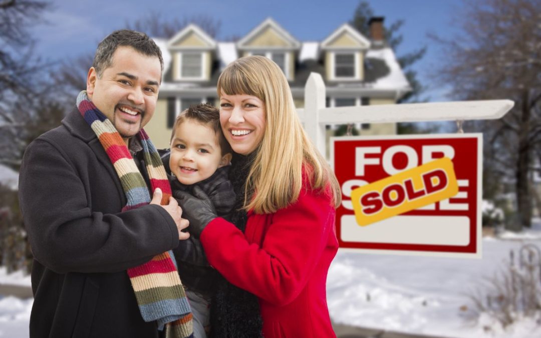 A happy looking mum, dad and son stood outside their new home with snow on the ground