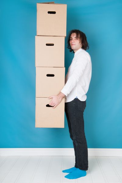 A man stood holding a stack of four packing boxes