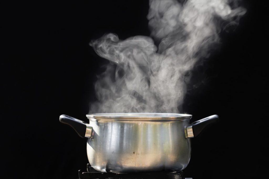 A boiling pan of water with plenty of steam