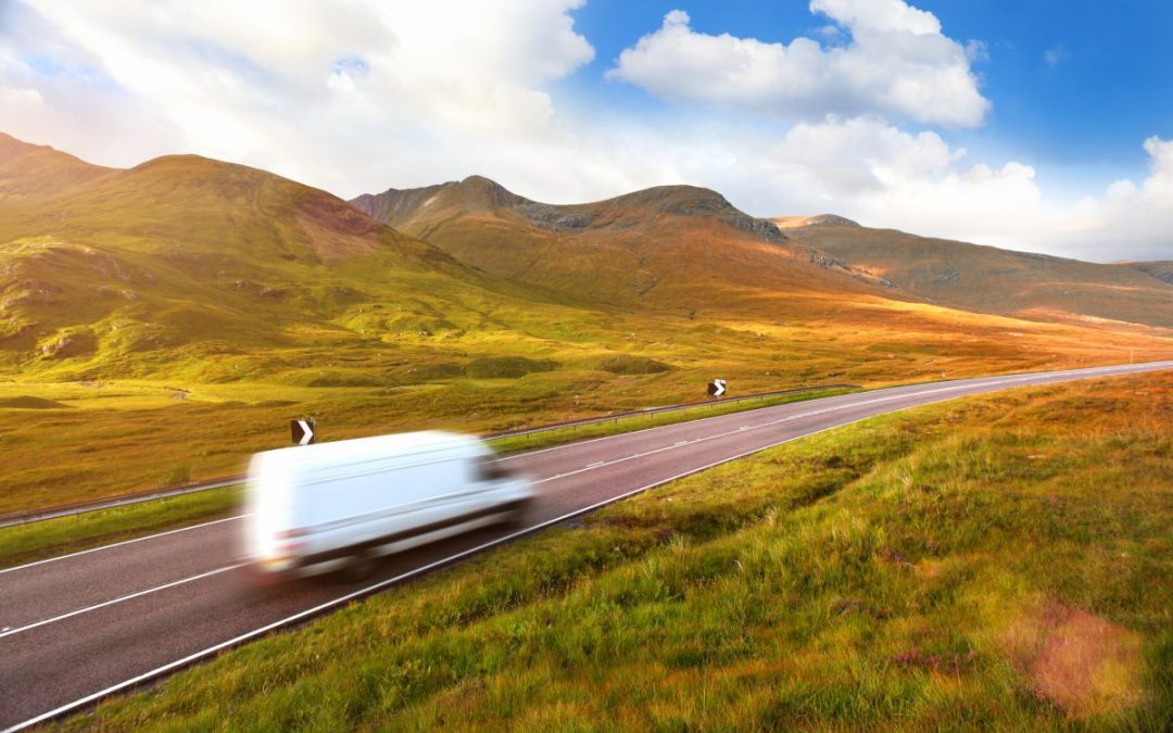 A white removals truck passing along a road in the Scottish Highlands