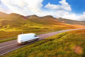 A white removals truck passing along a road in the Scottish Highlands