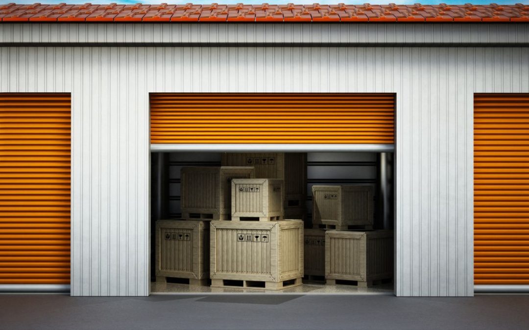 An external view of an open roller shutter door and crated belonging inside a storage room