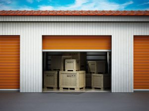 An external view of an open roller shutter door and crated belonging inside a storage room