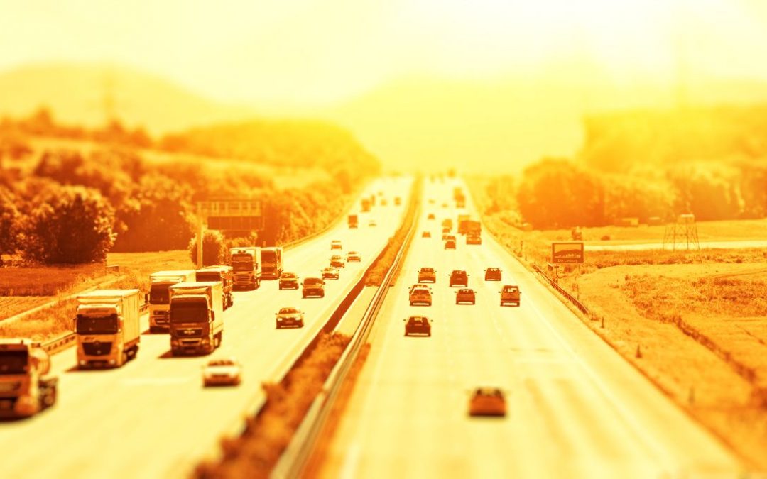 A busy multi-lane motorway bathed in golden light from the setting sun