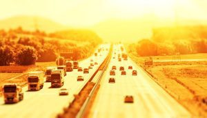 A busy multi-lane motorway bathed in golden light from the setting sun