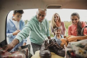 A happy family unloading bags from their car for a camping adventure