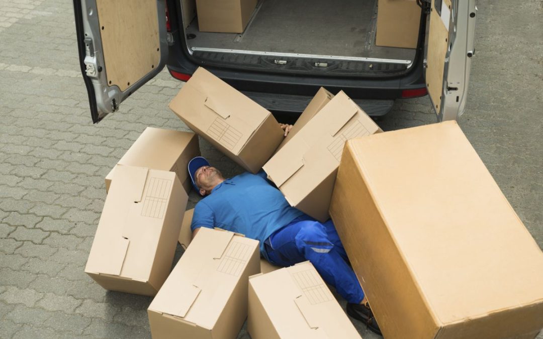 A delivery driver laying on the floor surrounded by cardboard boxes