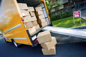 A removals van with easy access ramp loaded with packing boxes outside a property for rent