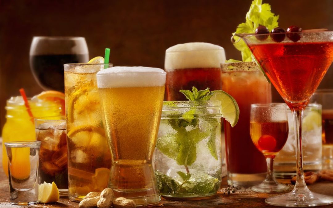 A large selection of alcholic wines, beers and cocktails in a variety of different sizes and shapes of glasses