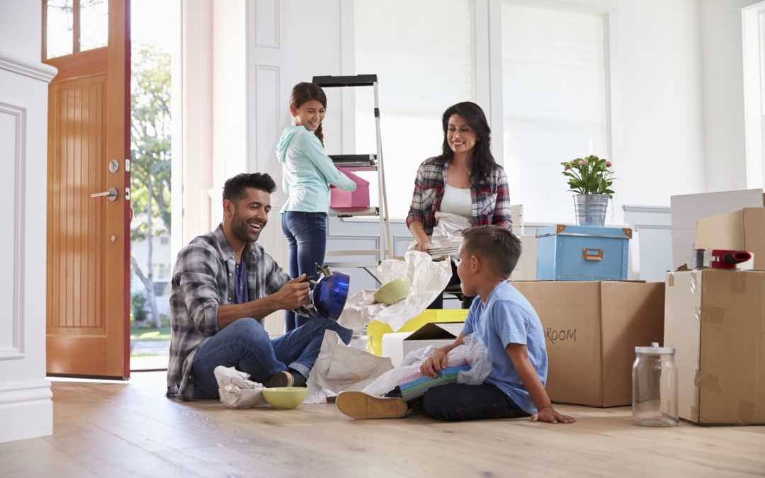 A family sat in their new home unpacking household belonging from cardboard packing boxes