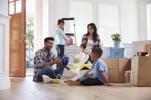 A family sat in their new home unpacking household belonging from cardboard packing boxes
