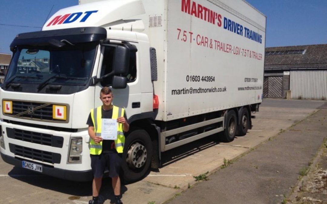 A removals lorry driver holding up his pass certificate in front of the driver training lorry