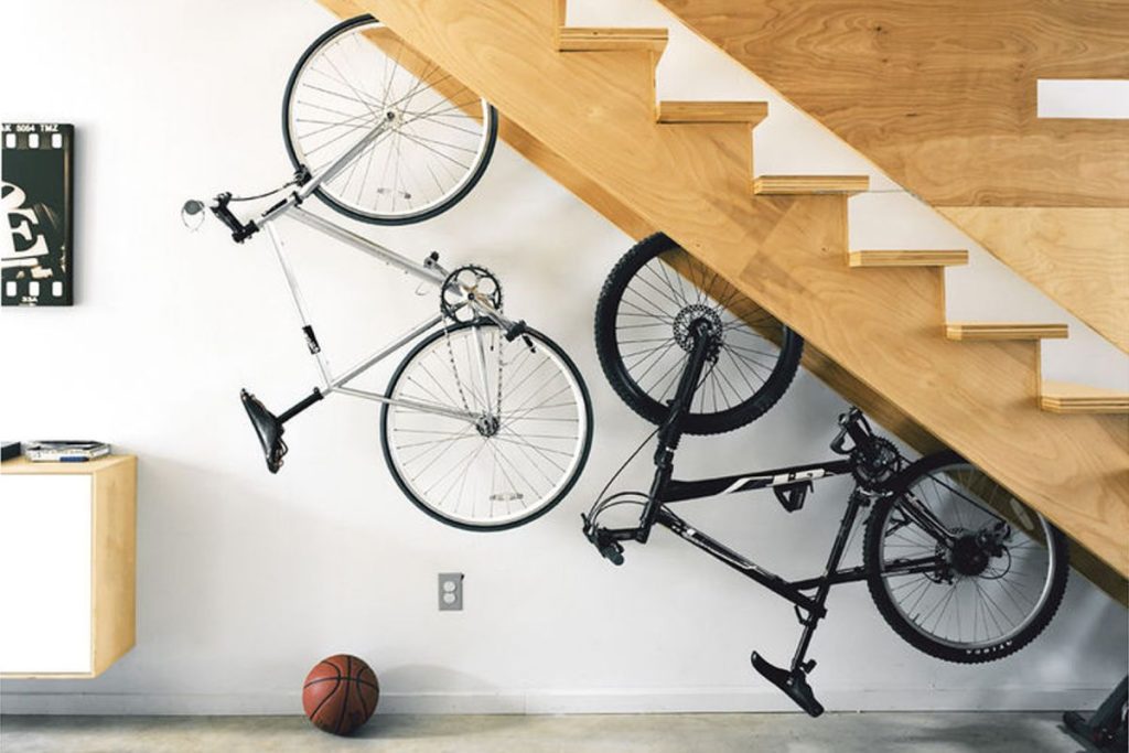 Unusual storage solution for bicycles suspended upside down under a wooden staircase