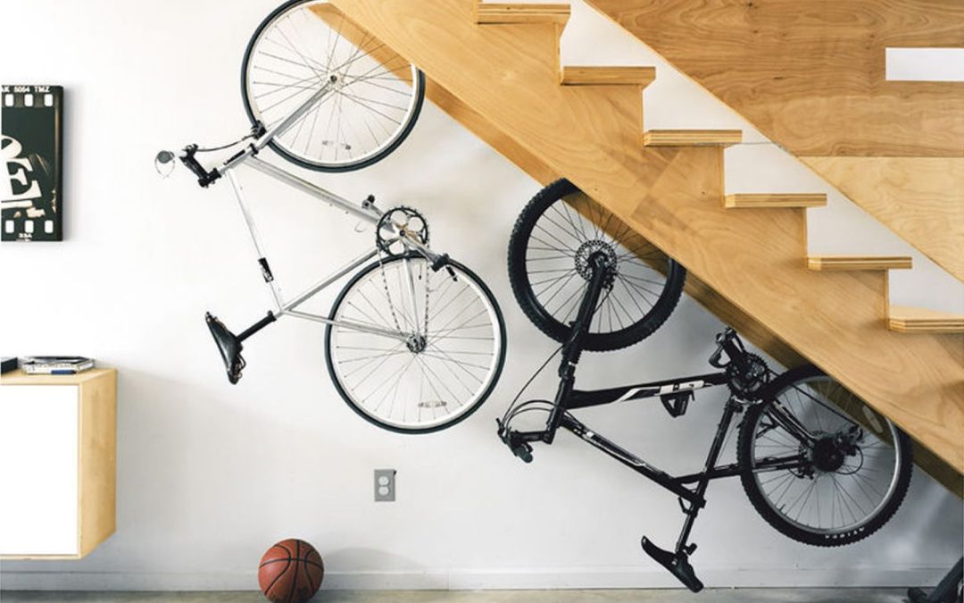 Unusual storage solution for bicycles suspended upside down under a wooden staircase