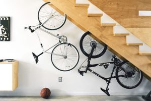 Unusual storage solution for bicycles suspended upside down under a wooden staircase