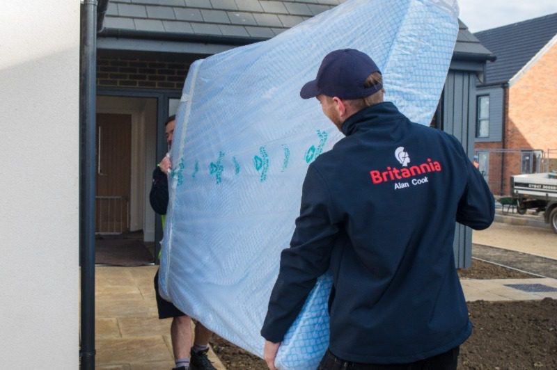 Two of our removals team carrying a protective wrapped mattress into a new house
