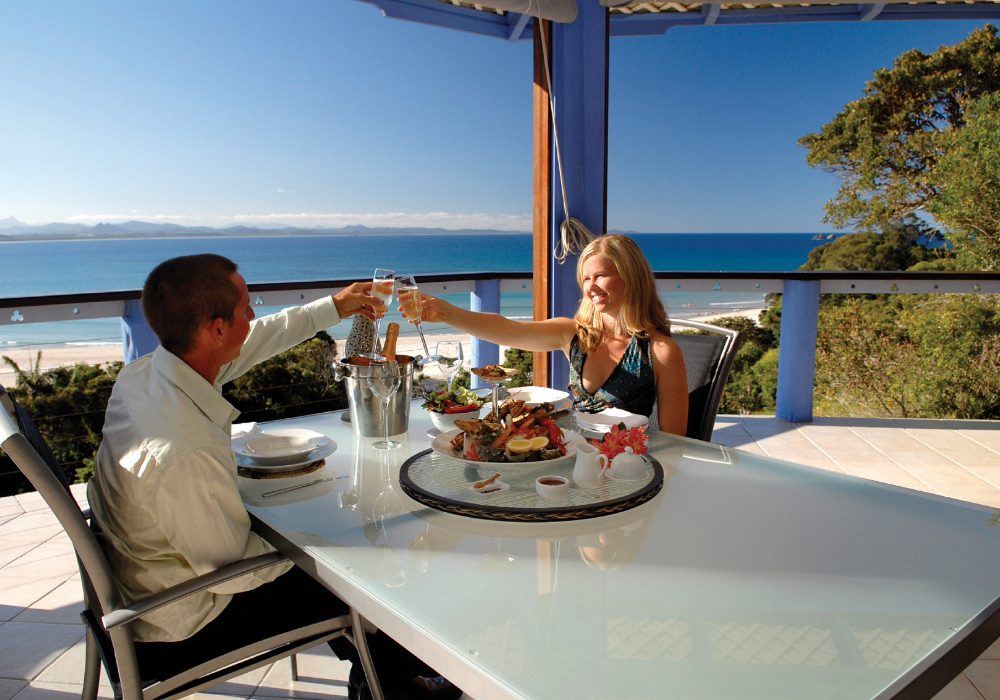Couple living in Australia A couple toasting drinks and having food by the beach in Australia
